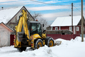 Yellow backhoe loader with hydraulic arm and front-mounted blade clears snow using high-traction...