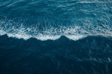 Hyper-realistic aerial view of a dark blue ocean wave in a minimalist style, captured in high resolution with cinematic lighting from a top-down perspective for a stunning visual effect