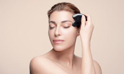 Woman using gua sha tool for facial massage and skincare