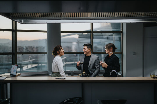 Three business professionals enjoy a coffee break in a sleek office setting, fostering collaboration and teamwork. The relaxed environment promotes creativity and open communication among colleagues.