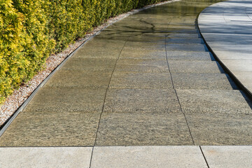 City park Krasnodar. Artificial swift river with granite banks runs around evergreen hedge with...