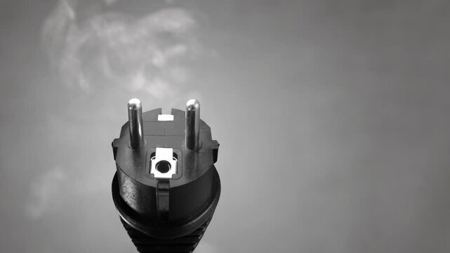 Close up of an electrical plug emitting smoke