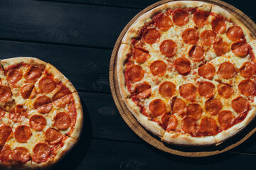 Top view of pepperoni pizzas on dark wooden table in natural light