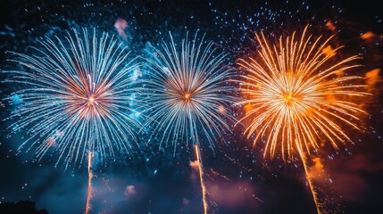 Naklejka premium Vibrant fireworks light up the night sky with dazzling displays of blue, orange, and gold. A spectacular celebratory scene!