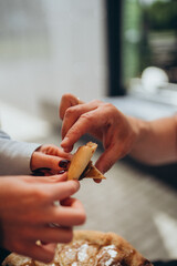 Close-up of hands passing a slice of caramelized apple dessert pizza, human interaction during cozy snack time, warm sweet pastry with visible sugar glaze and cinnamon