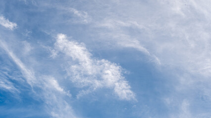 Serene view of a vibrant blue sky adorned with soft, delicate white clouds on a bright day. The tranquil heavens inspire peace, freedom, and the beauty of nature's simplicity.
