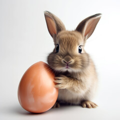 Obraz premium Cute bunny holding large Easter egg against white background. Soft fur and bright eyes create warm and festive feeling. Perfect for Easter decorations, greeting cards and holiday promotions