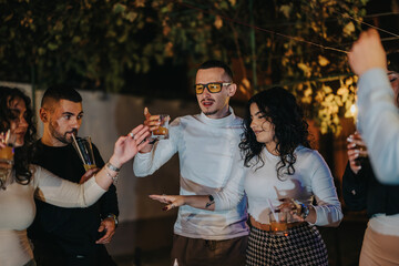 A group of friends enjoying an evening gathering outdoors, sharing drinks and cheerful discussions under a pleasant ambiance, depicting camaraderie and relaxation.
