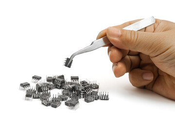 Precision hand use of tweezers to pick up integrated circuit components at a workbench