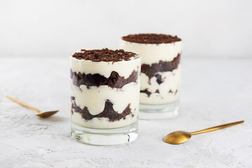 Cherry, vegan cream with shea butter and chocolate biscuit layered dessert in glasses on a light background. Black forest trifle.