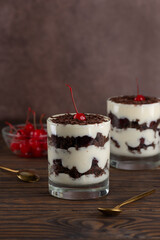 Dessert cherry Black forest or Schwarzwald cupcakes in a glasses on a brown wooden table. Vegan dessert. Vertical orientation.