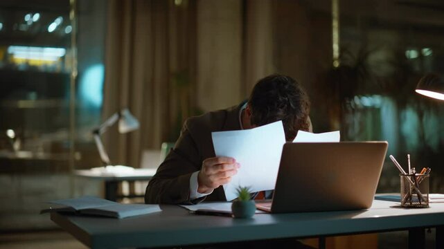 Tired man working overtime sitting dark workspace closeup. Sleepy businessman