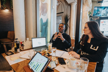 Diverse business professionals engaging in a strategic discussion during a meeting. The setting is a stylish and modern cafe, with laptops and charts aiding their collaborative brainstorming session.