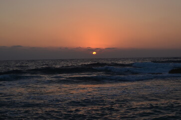 Serene sunset over calm ocean waves with clear sky and soft light