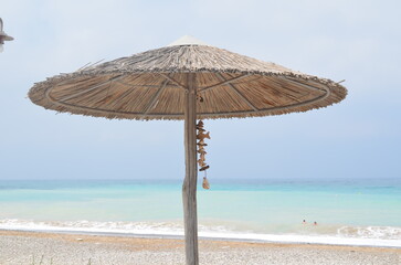 Sunny beach with straw umbrella overlooking turquoise sea