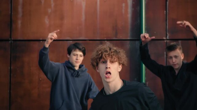 Young male dancers voguing with synchronized choreography, expressing dynamic movements against metallic brown background