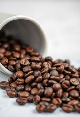 Fototapeta premium Close-up of roasted coffee beans spilling from a ceramic coffee cup, background, burlap, grinder