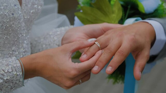 Newlyweds put wedding gold rings on each other