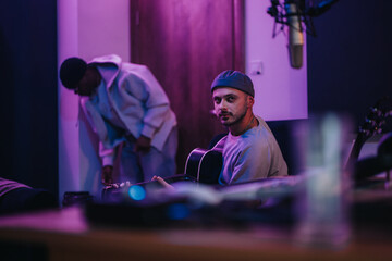 Musicians engaged in a creative session within a dynamic recording studio, capturing artistic collaboration. The atmosphere is lively, with a focus on teamwork and musical expression.