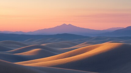 Serene sunrise over rolling sand dunes and distant mountains
