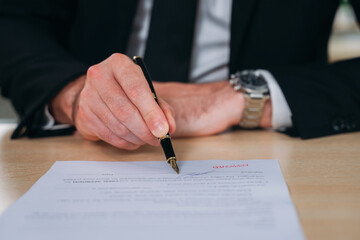 A business man is writing on a piece of paper with a pen