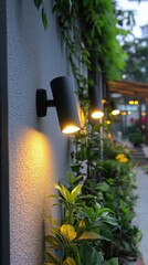 Serene outdoor ambiance with modern black sconce lighting illuminating textured wall and lush green foliage in a tranquil setting