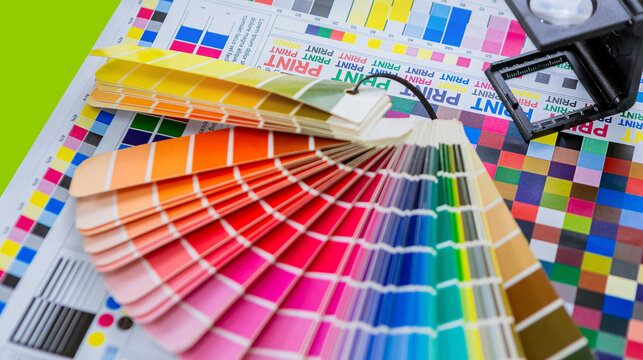 Team graphic designer checking print quality of media graphics proof print and color guides in printing industry. Selected focus	