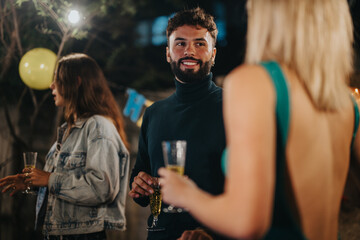 An outdoor celebration with friends enjoying drinks and cheerful conversation under festive lighting.