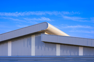 Fototapeta premium Industry factory building with aluminium louver ventilation on gray corrugated steel wall and pitched roof in modern style against blue sky background