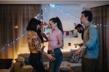 A lively group of friends celebrates a birthday in a cozy living room with music and dancing. Festive decorations enhance the joyful atmosphere, creating a perfect setting for an intimate gathering.