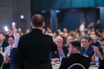 Confident speaker engaging with attentive audience at a corporate seminar, discussing important topics.