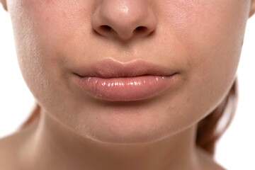 Fototapeta premium Close-up shot of a woman's natural lips, showing subtle texture and sheen. Neutral skin tone, cropped view on white background