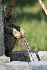 A tiny well with water coming from a bucket