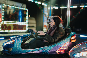 Two friends share laughter and joy while riding bumper cars at a vibrant amusement park. The shining lights and festive atmosphere evoke a sense of fun and winter holiday excitement.