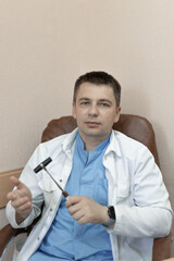 Male doctor holding a reflex nerve tapping instrument in his hand
