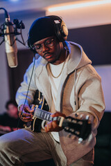 An artist composes music in a recording studio, wearing headphones and casual attire, focused on...