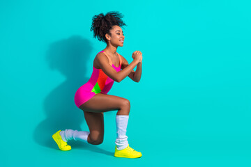 Young sportswoman in vibrant athletic outfit engaging in workout against her teal studio backdrop...