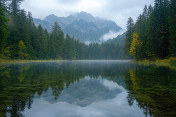 Fototapeta premium Lake Surrounded by Autumnal Forest and Misty Mountains
