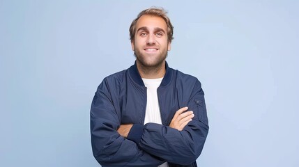 A smiling man with crossed arms posing on a blue background
