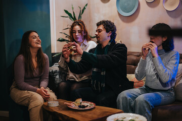 A group of friends socializing and sharing food in a warm, comfortable lounge environment.