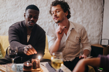 Two individuals in a warm, inviting setting enjoying a relaxing evening lighting candles. Wine glasses and a cozy atmosphere enhance this moment centered around camaraderie and tranquil companionship.
