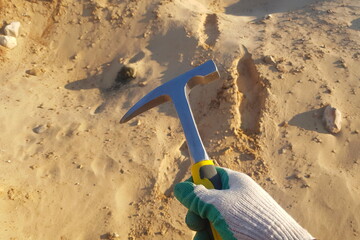 Sharpened geological hammer in hand, searching for fossils and minerals in a quarry