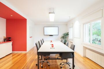 Modern conference room with red accent wall and screen in office
