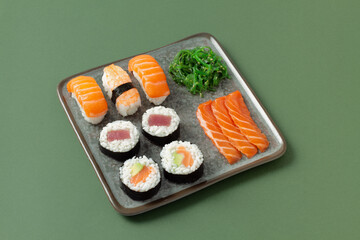 Variety of sushi on a ceramic plate with green background