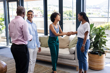 Greeting each other, diverse professionals networking and smiling in modern office