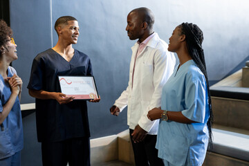 Medical diverse professionals celebrating colleague receiving certificate, at conference hall