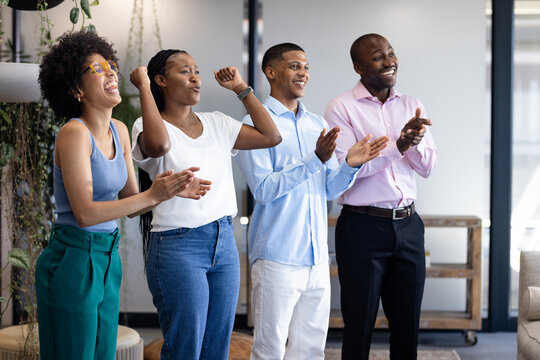 Business diverse team celebrating success, clapping and smiling in modern office space