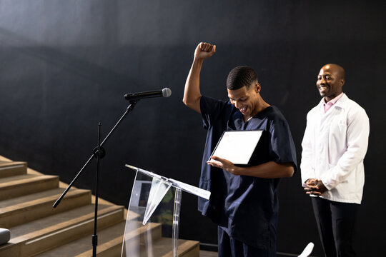 Celebrating achievement on stage, man with certificate, at conference hall, copy space