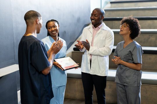 Celebrating colleague's achievement, medical diverse team with certificate, at conference hall