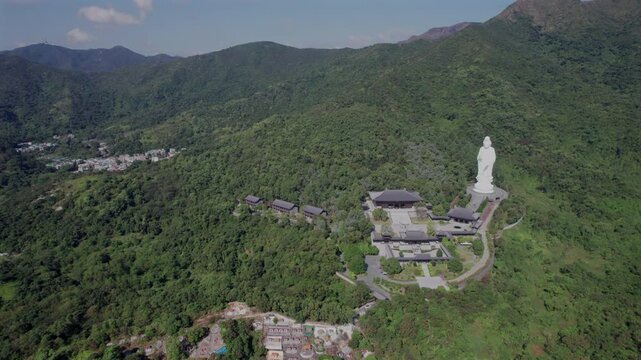 Drone view of Tsz Shan Monastery with large white Budha statue nestles on a lush hill under blue sky
